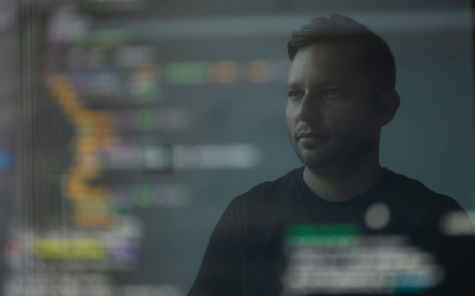 Un développeur devant son écran de code, dans une pièce sombre.
